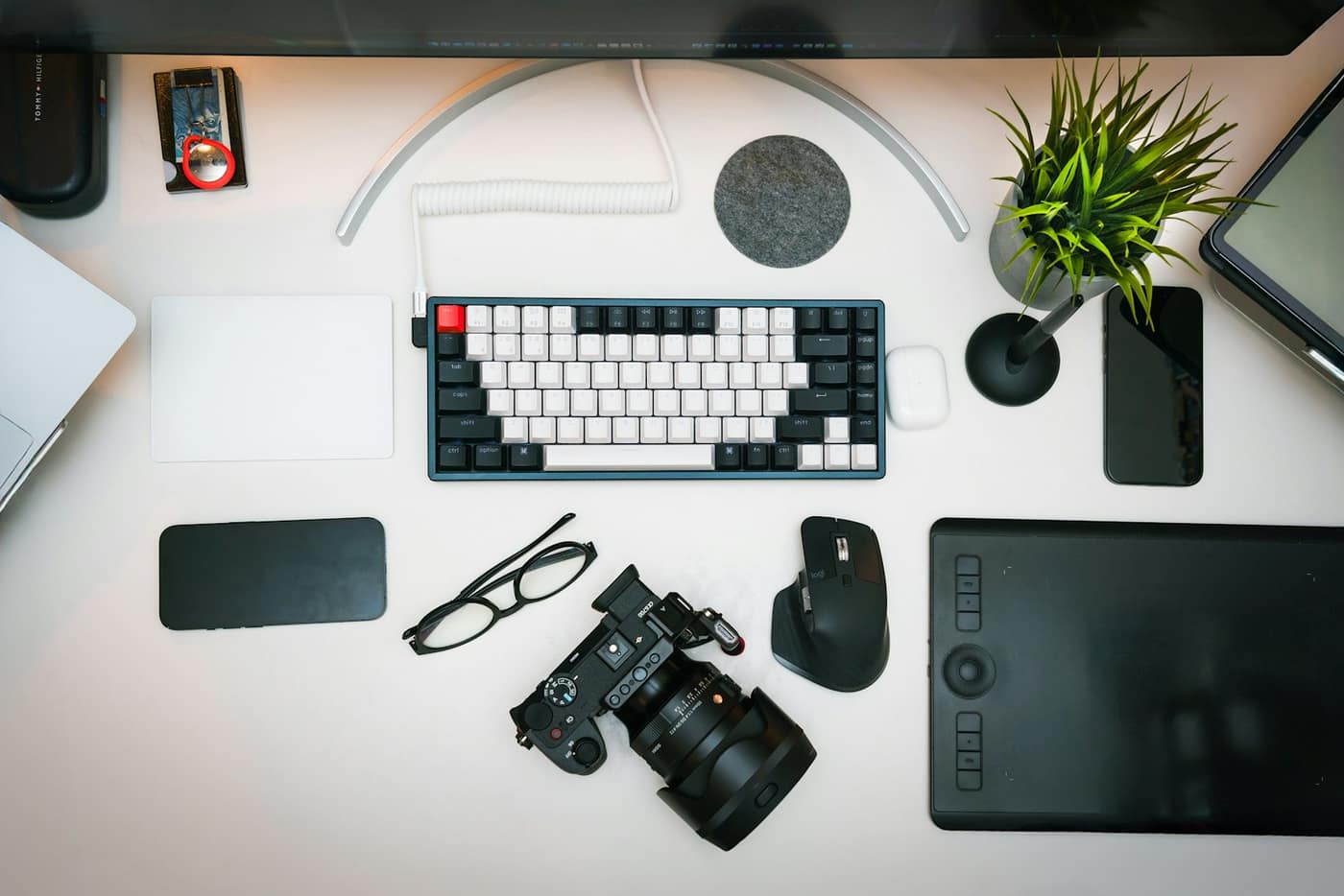 A calm creative workspace with a camera, keyboard and drawing tablet